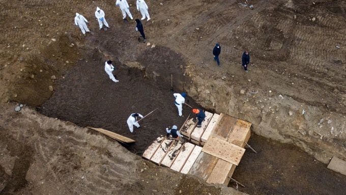 Overhead view depicting Coronavirus victims being buried in coffins in a mass grave in New York.
